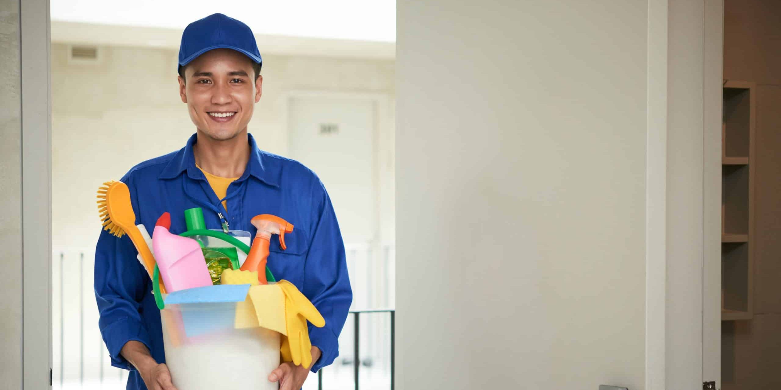 cheerful-asian-male-janitor-walking-into-hotel-room-carrying-supplies-bucket-scaled-e1718030965273.jpg